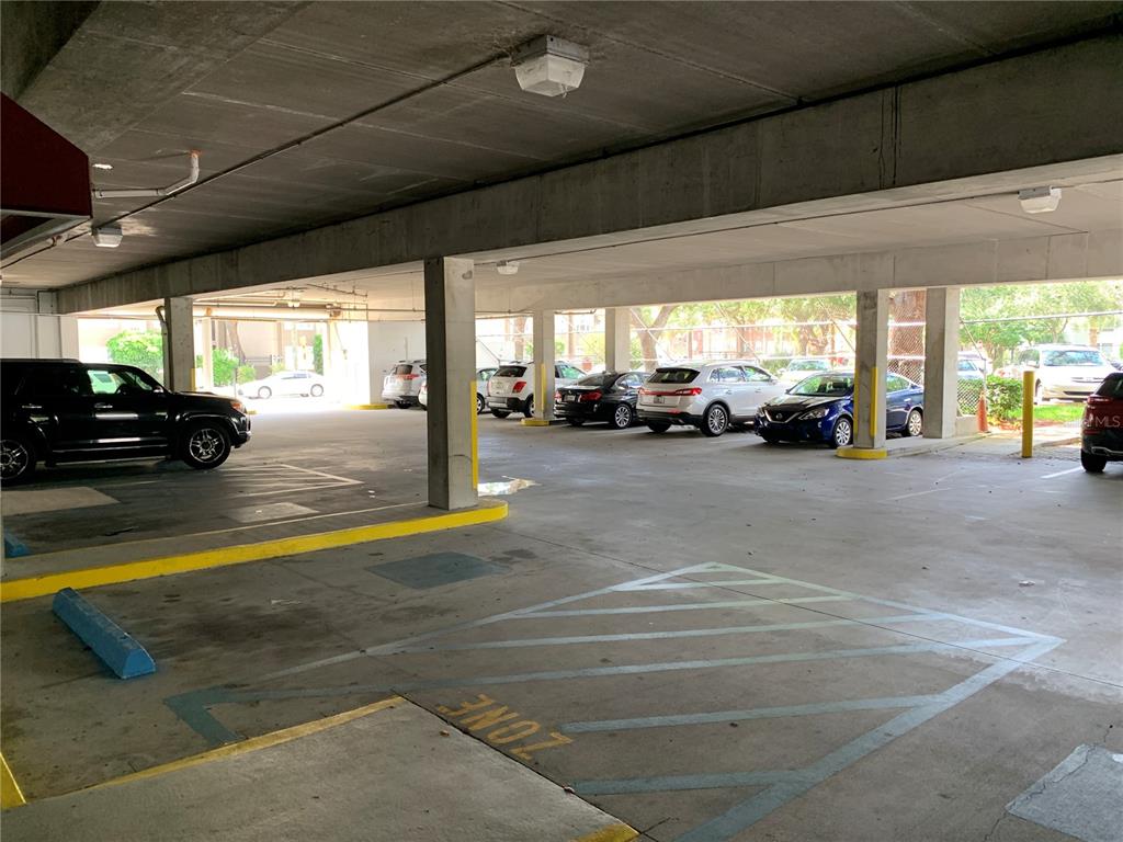 A covered parking garage features several parked cars and concrete support pillars — 2111 W SWANN AVENUE, TAMPA, FL