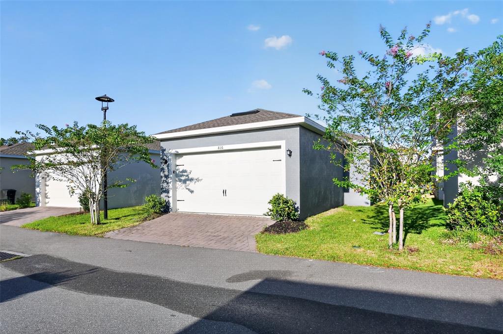 A gray house with a white garage door and a brick driveway under a blue sky — 816 MIDDLETON STREET, DEBARY, FL