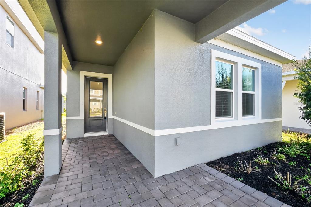A gray stucco house exterior features a covered entryway with a paver walkway and windows — 816 MIDDLETON STREET, DEBARY, FL