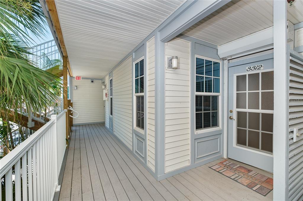 A covered wooden walkway leads to the entrance of a building with light-colored siding — 7454 PLACIDA ROAD UNIT 3312, PLACIDA, FL