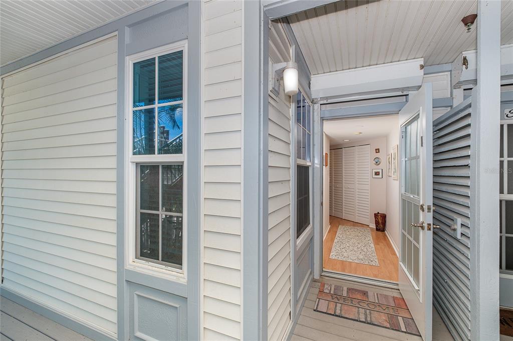 An exterior view of a home entrance with white siding, a window, and an open door — 7454 PLACIDA ROAD UNIT 3312, PLACIDA, FL