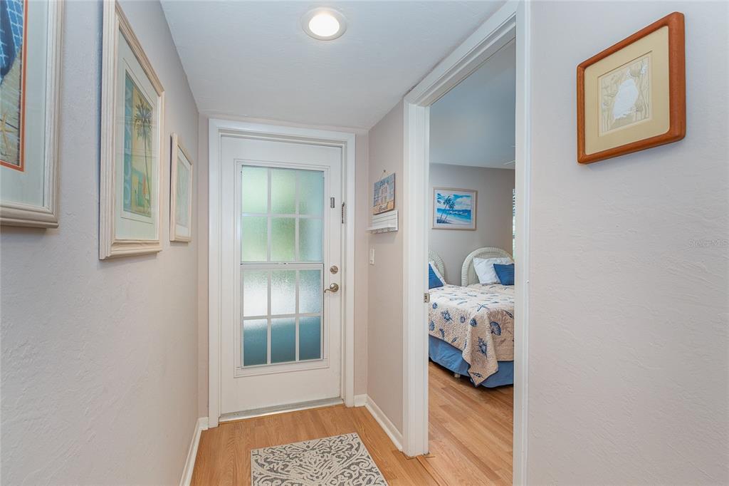 A hallway with light wood floors leads to a front door and a bedroom entrance — 7454 PLACIDA ROAD UNIT 3312, PLACIDA, FL