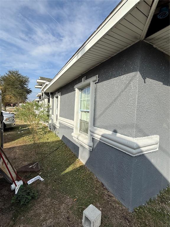 The exterior of a gray stucco house features decorative white trim around the windows — 313 E WASHINGTON STREET, AVON PARK, FL