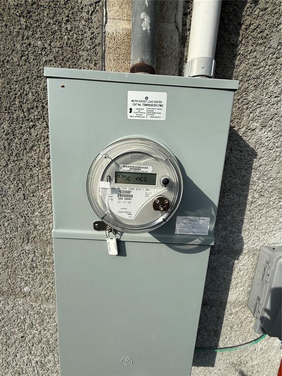 A gray electrical meter box is mounted on a textured exterior wall — 313 E WASHINGTON STREET, AVON PARK, FL