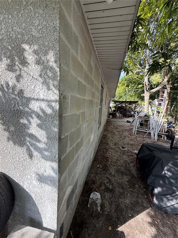 A side view of a house exterior showing a concrete block wall and stucco finish — 313 E WASHINGTON STREET, AVON PARK, FL