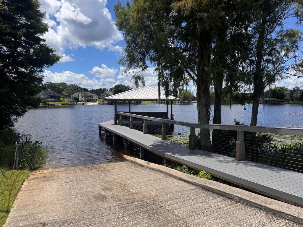 A concrete boat ramp leads to a wooden dock with a covered gazebo on a lake — 10642 CRESCENT LAKE COURT, CLERMONT, FL