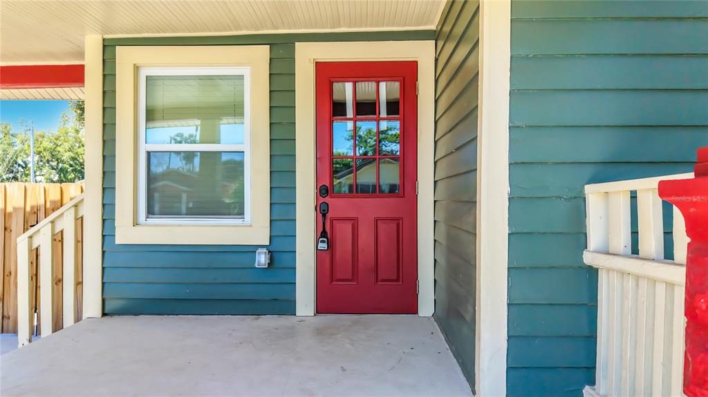 A red front door with a window sits on a porch with blue siding — 1435 PRESCOTT STREET S, ST PETERSBURG, FL