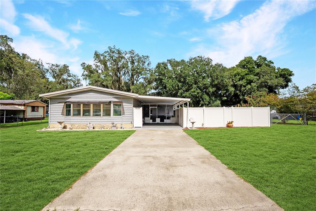 A single-story house with a concrete driveway, a carport, and a white privacy fence — 9529 SW 30TH TERRACE, OCALA, FL