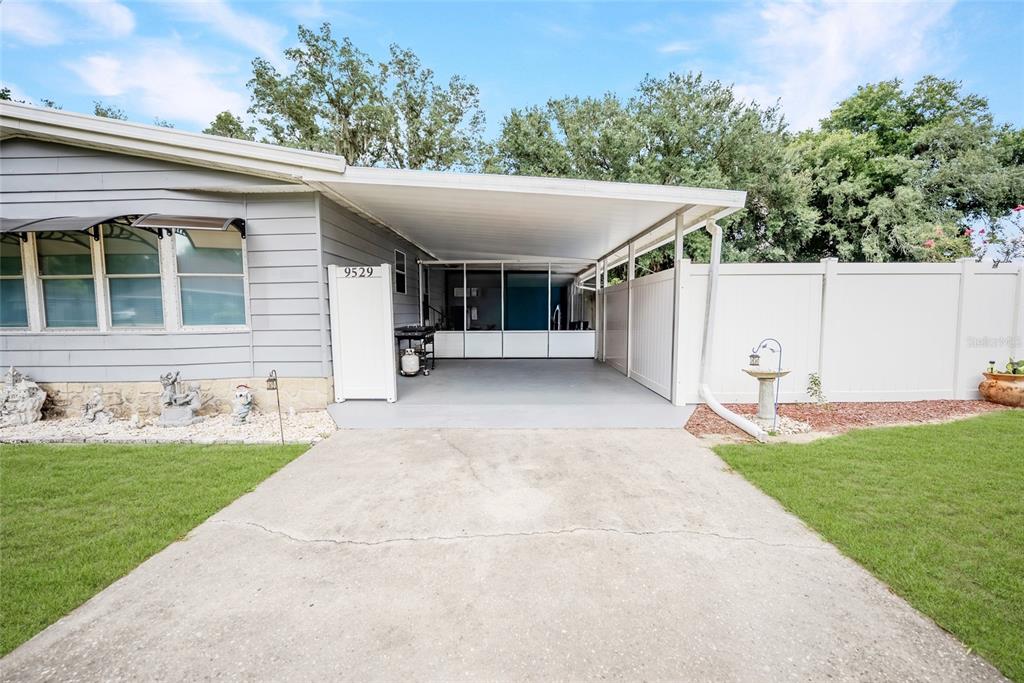 A single-story home features a concrete driveway, a covered carport, and a white privacy fence — 9529 SW 30TH TERRACE, OCALA, FL