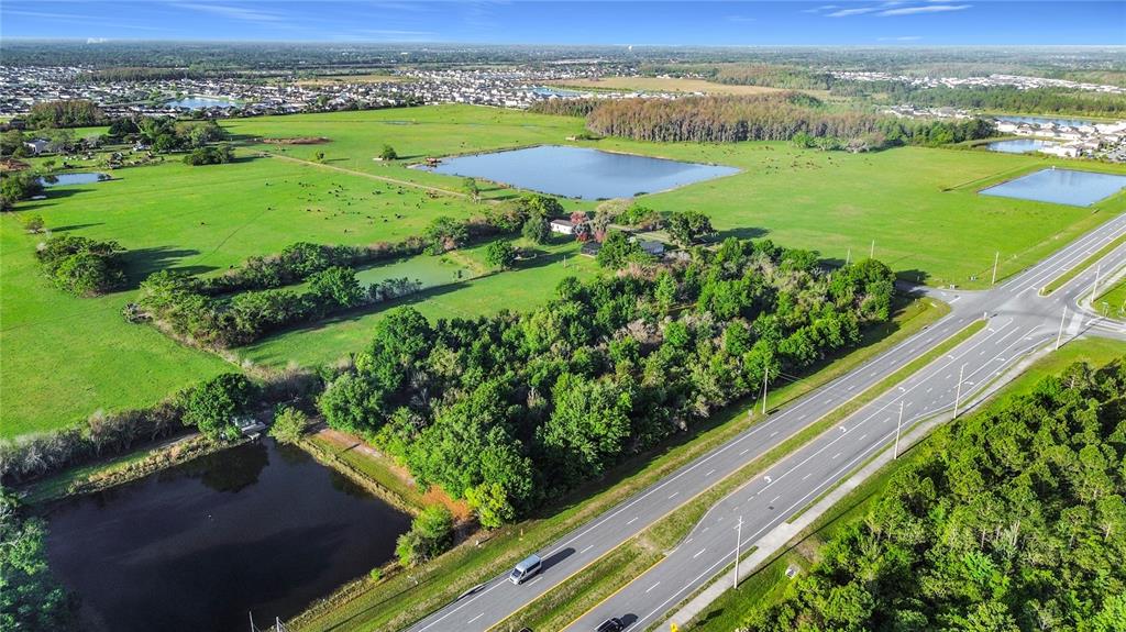 An aerial view shows a large grassy field with several ponds and a multi-lane road — 0000 OLD HICKORY TREE ROAD, ST CLOUD, FL