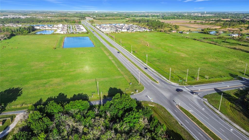 An aerial view shows a rural intersection with a large pond and nearby residential developments — 0000 OLD HICKORY TREE ROAD, ST CLOUD, FL