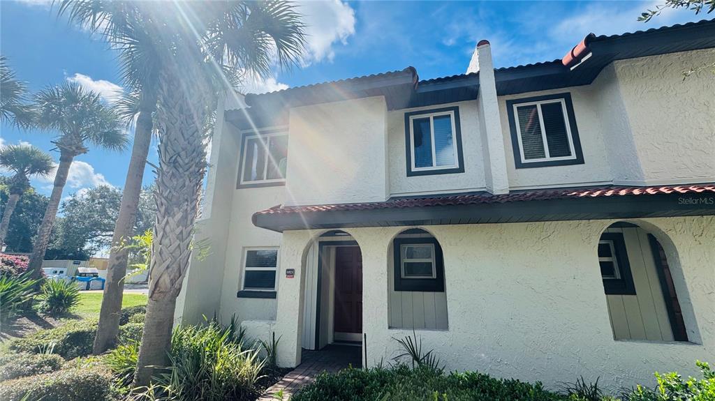 A two-story townhouse with a stucco exterior, arched entryway, and palm trees in the front — 1021 BASEBALL AND BOARDWALK COURT, KISSIMMEE, FL