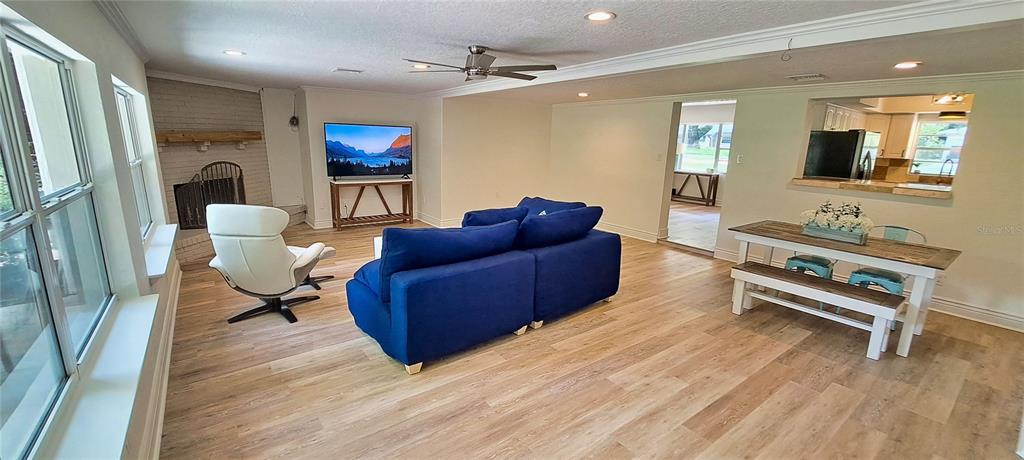 An open-concept living and dining area features light wood flooring, a blue sofa, and a fireplace — 3017 BAY LAKE ROAD, ORLANDO, FL