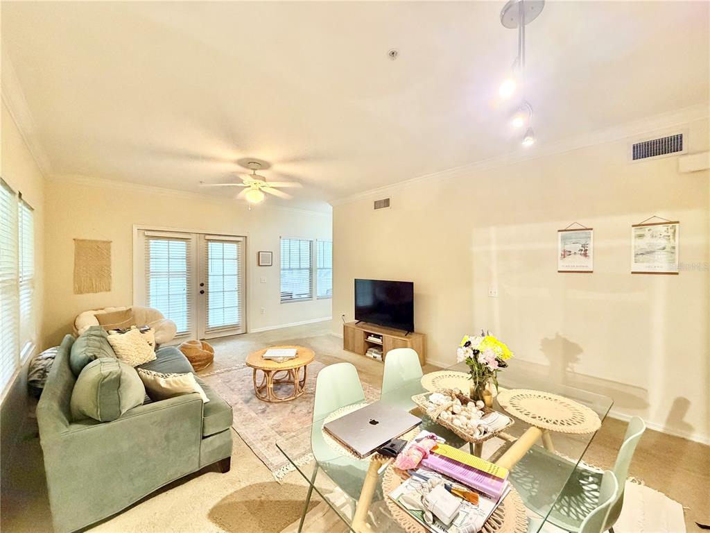 A living and dining area features a green sofa, glass table, and television on console — 9177-203 SW 52ND ROAD UNIT 203, GAINESVILLE, FL