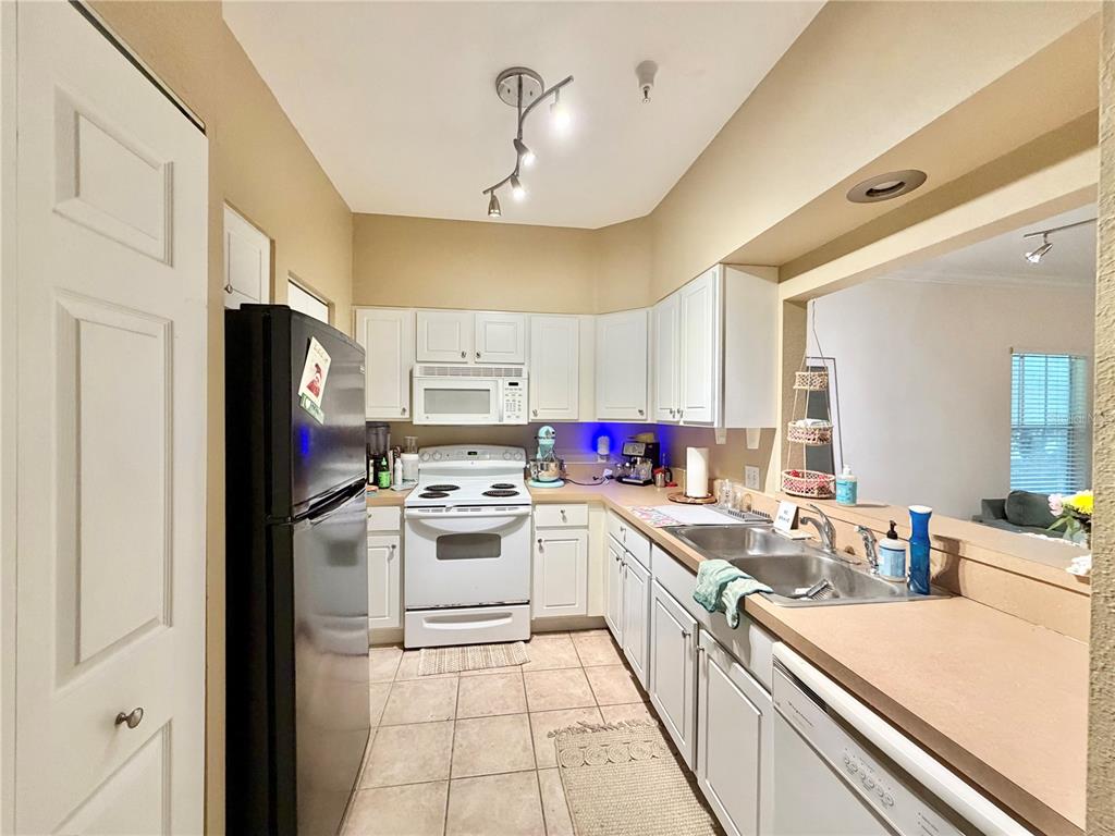 A kitchen features white cabinets, a black refrigerator, a white stove, and a double sink — 9177-203 SW 52ND ROAD UNIT 203, GAINESVILLE, FL