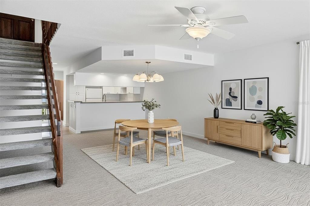 A dining area with a round wooden table, chairs, and a staircase in a room — 301 S GULF BOULEVARD UNIT 11, PLACIDA, FL