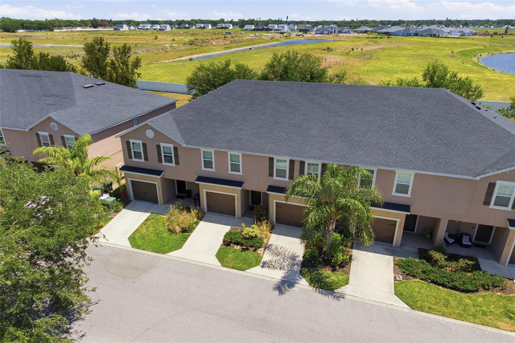 An aerial view of a multi-unit townhouse complex with attached garages and a grassy field — 1306 GRANTHAM DRIVE, SARASOTA, FL