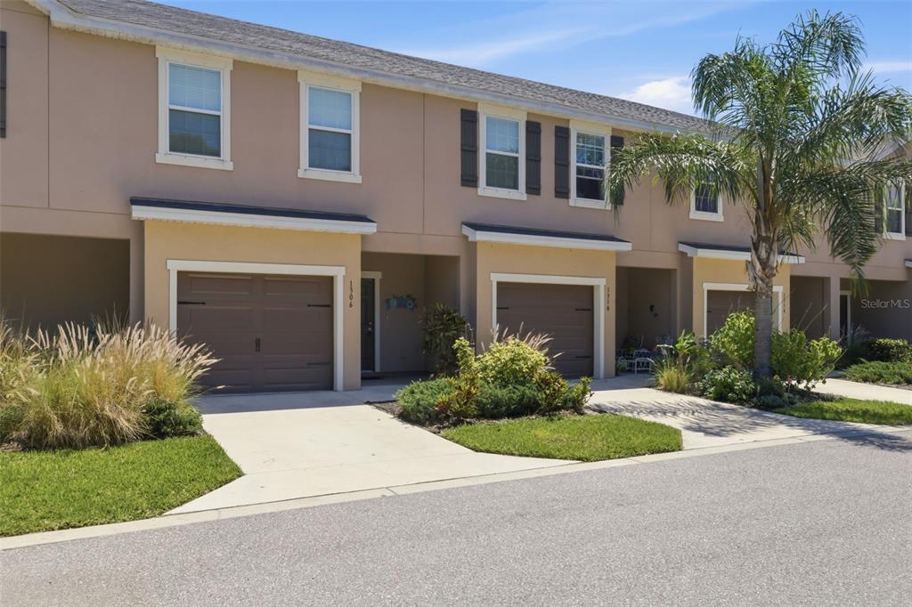 A row of two-story townhomes with beige stucco exteriors, attached garages, and small front lawns — 1306 GRANTHAM DRIVE, SARASOTA, FL