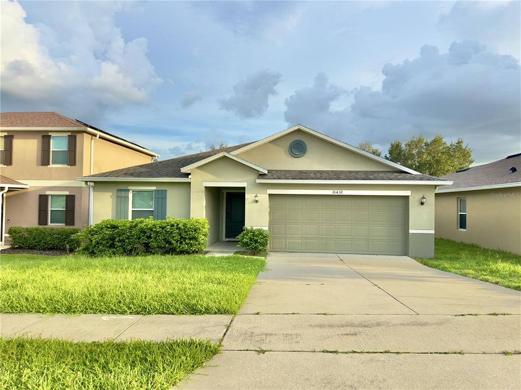 A single-story house with a green exterior, a two-car garage, and a concrete driveway — 16432 CAJU ROAD, CLERMONT, FL