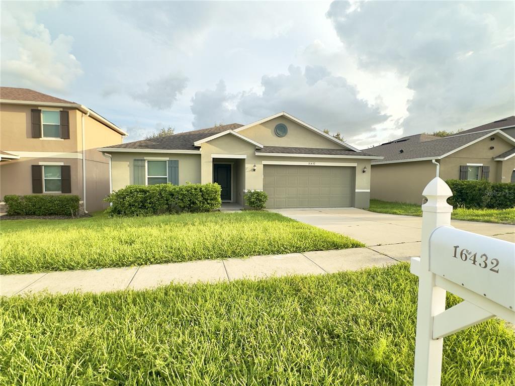 A single-story suburban house with a two-car garage and a white mailbox in the foreground — 16432 CAJU ROAD, CLERMONT, FL