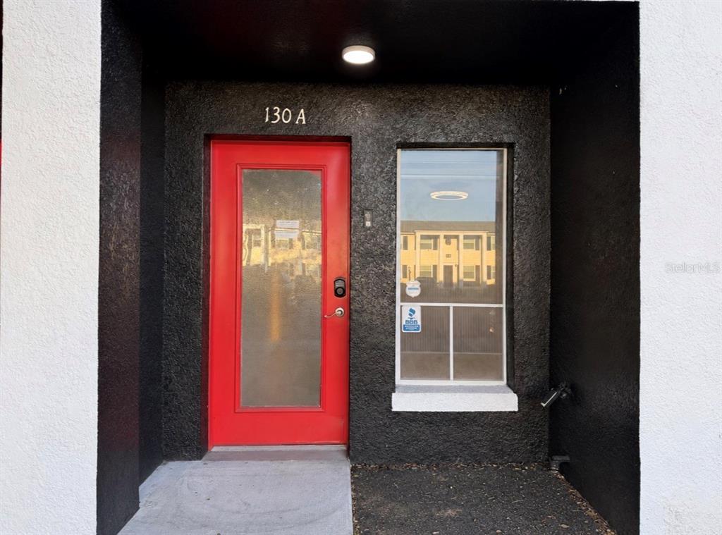 Two adjacent building entrances feature bright red doors and dark textured exterior walls — 130 S BUMBY AVENUE Unit A, ORLANDO, FL