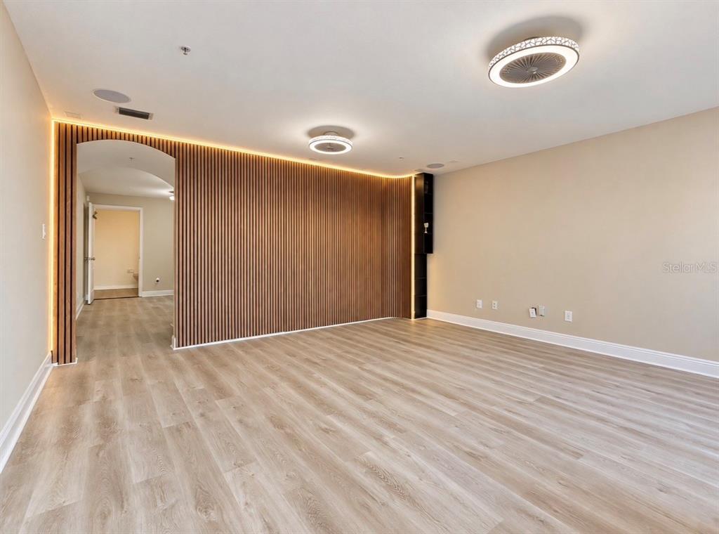An empty room features wood-look flooring, white wainscoting, a green accent wall, and two ceiling fans — 130 S BUMBY AVENUE Unit A, ORLANDO, FL