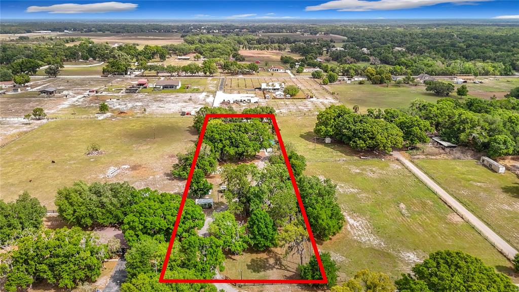 A screened-in swimming pool with a patio, red umbrella, and a detached building in back — 216 CORBETT ROAD, LITHIA, FL
