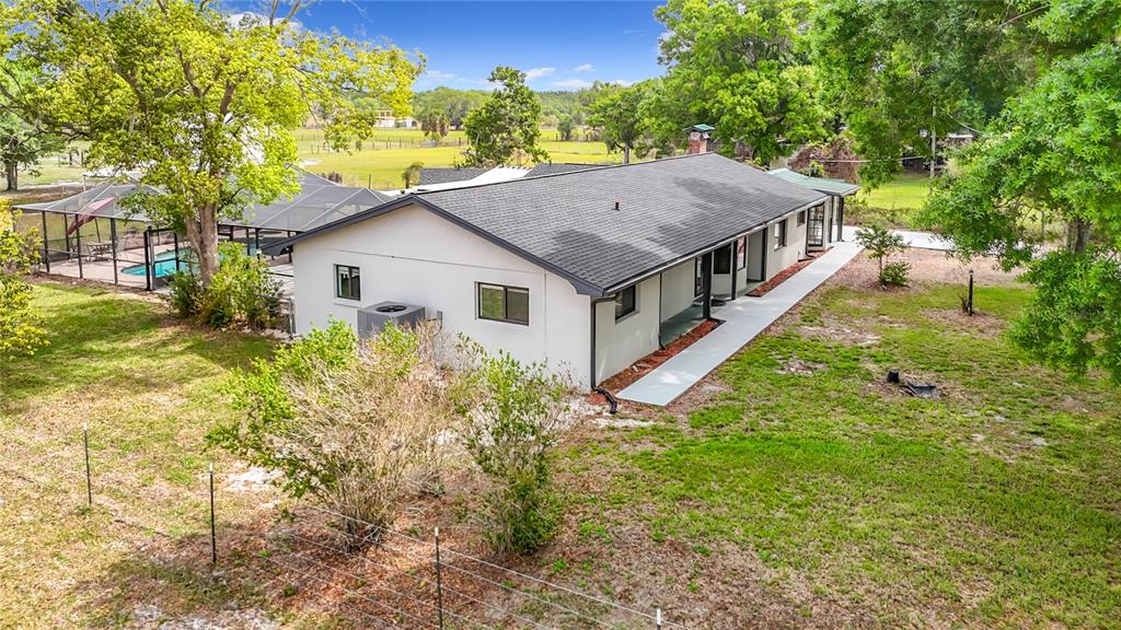 A screened-in patio features a swimming pool, brick pavers, and outdoor furniture at sunset — 216 CORBETT ROAD, LITHIA, FL