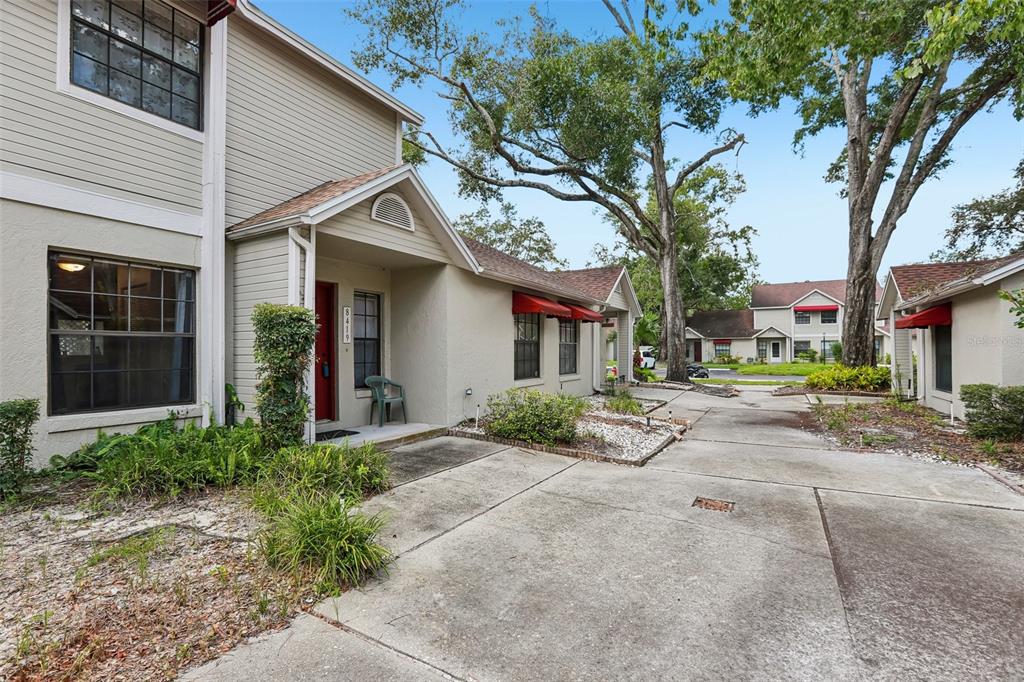 A two-story tan townhouse with a red front door and a concrete driveway — 8419 LAURELON PLACE, TEMPLE TERRACE, FL