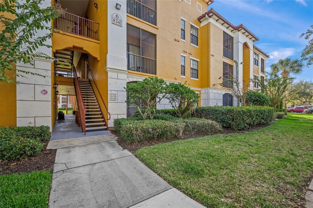 An exterior view of a yellow three-story apartment building with an outdoor staircase — 8341 38TH STREET CIRCLE E UNIT 303, SARASOTA, FL