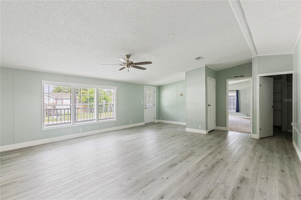 A spacious living room features light green walls, wood-look flooring, and a ceiling fan — 3518 KIAH DRIVE, WESLEY CHAPEL, FL
