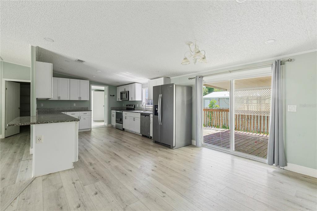 A kitchen with white cabinets, granite countertops, and stainless steel appliances opens to a deck — 3518 KIAH DRIVE, WESLEY CHAPEL, FL