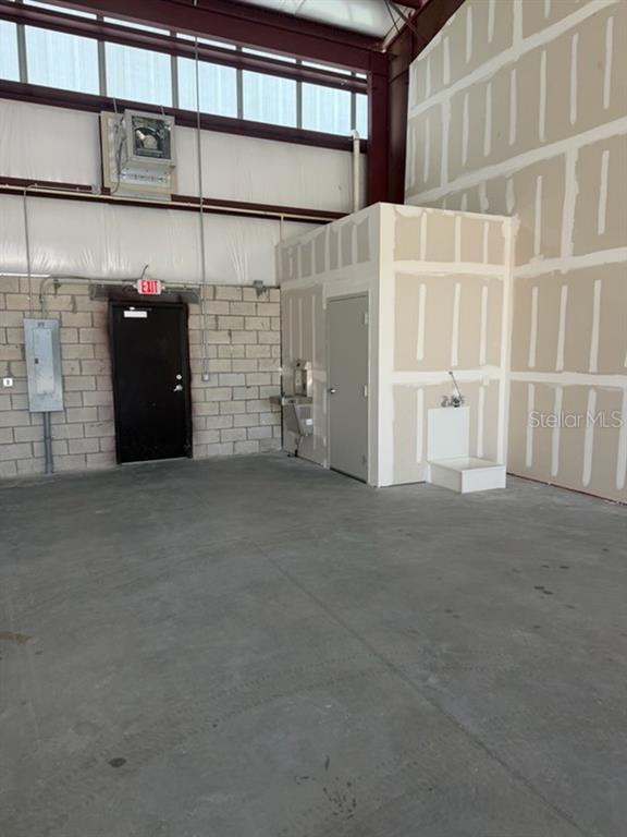 A long, single-story industrial warehouse building features multiple roll-up doors and a large asphalt parking lot — 2835 HAMMOND ROAD, FORT PIERCE, FL
