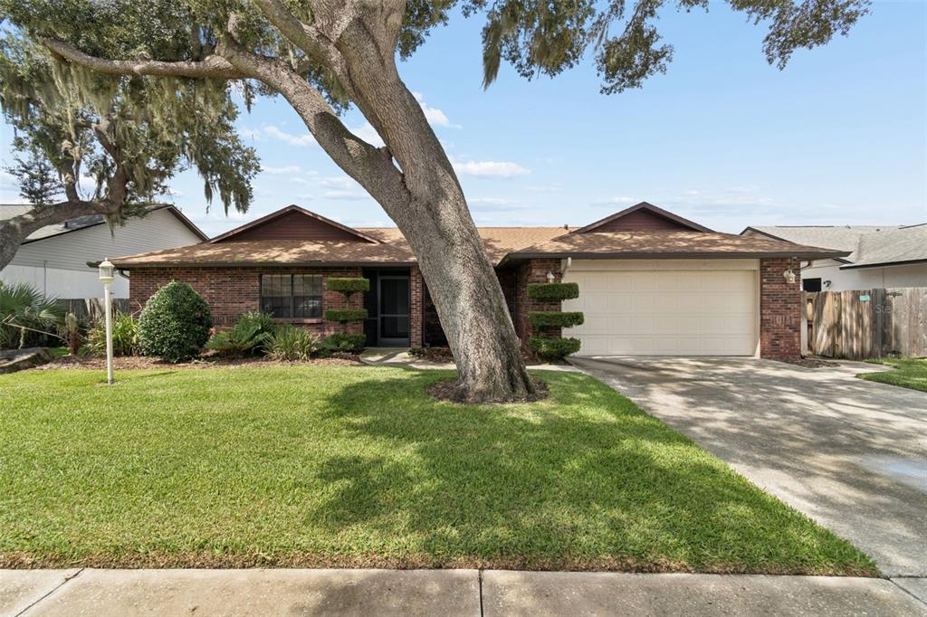 A single-story brick house with a large tree in the front yard and a garage — 653 TIMBER POND DRIVE, BRANDON, FL