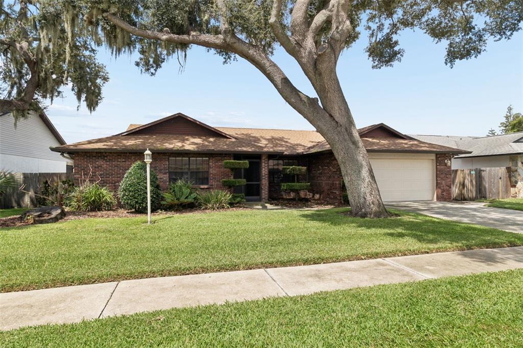 A single-story brick house with a large tree in the front yard and a garage — 653 TIMBER POND DRIVE, BRANDON, FL