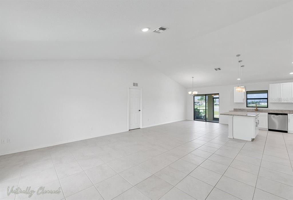 A bright, open-concept living area with white walls, light tile flooring, and a modern kitchen — 217 NE 20TH TERRACE, CAPE CORAL, FL