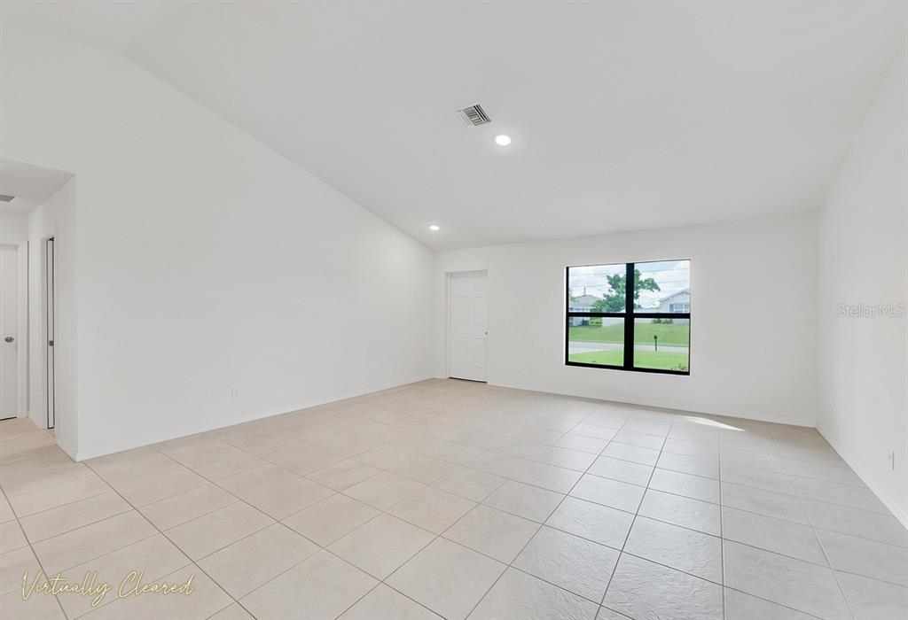 An empty room with white walls, tiled floors, a single window, and recessed lighting — 217 NE 20TH TERRACE, CAPE CORAL, FL