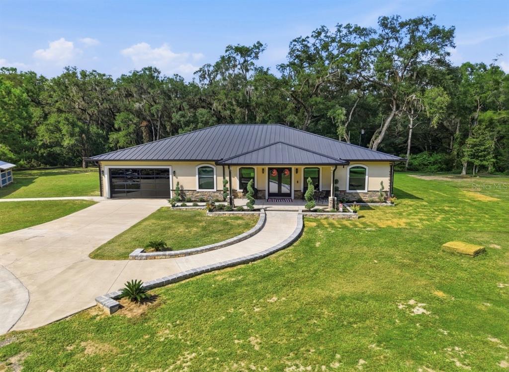 An exterior view of a single-story house with a metal roof and a curved walkway — 19826 NW 6TH AVENUE, NEWBERRY, FL
