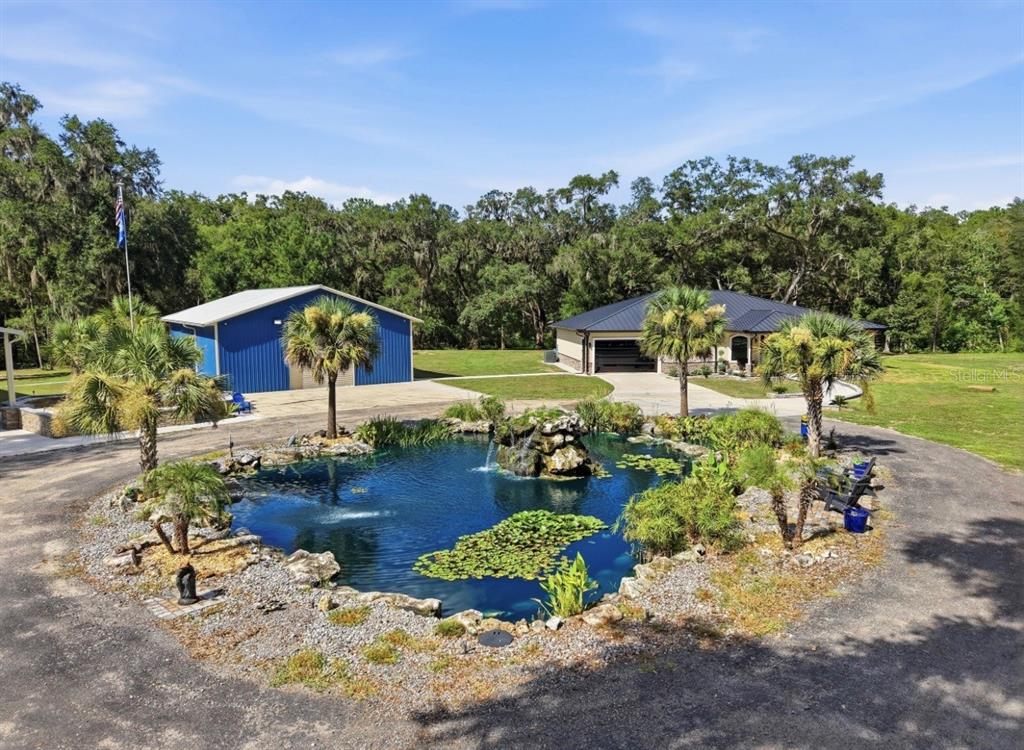 An aerial view shows a pond with a fountain in front of a house and garage — 19826 NW 6TH AVENUE, NEWBERRY, FL