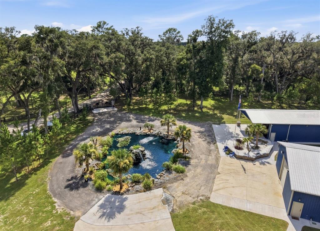 An aerial view shows a circular pond with a fountain, palm trees, and blue buildings — 19826 NW 6TH AVENUE, NEWBERRY, FL