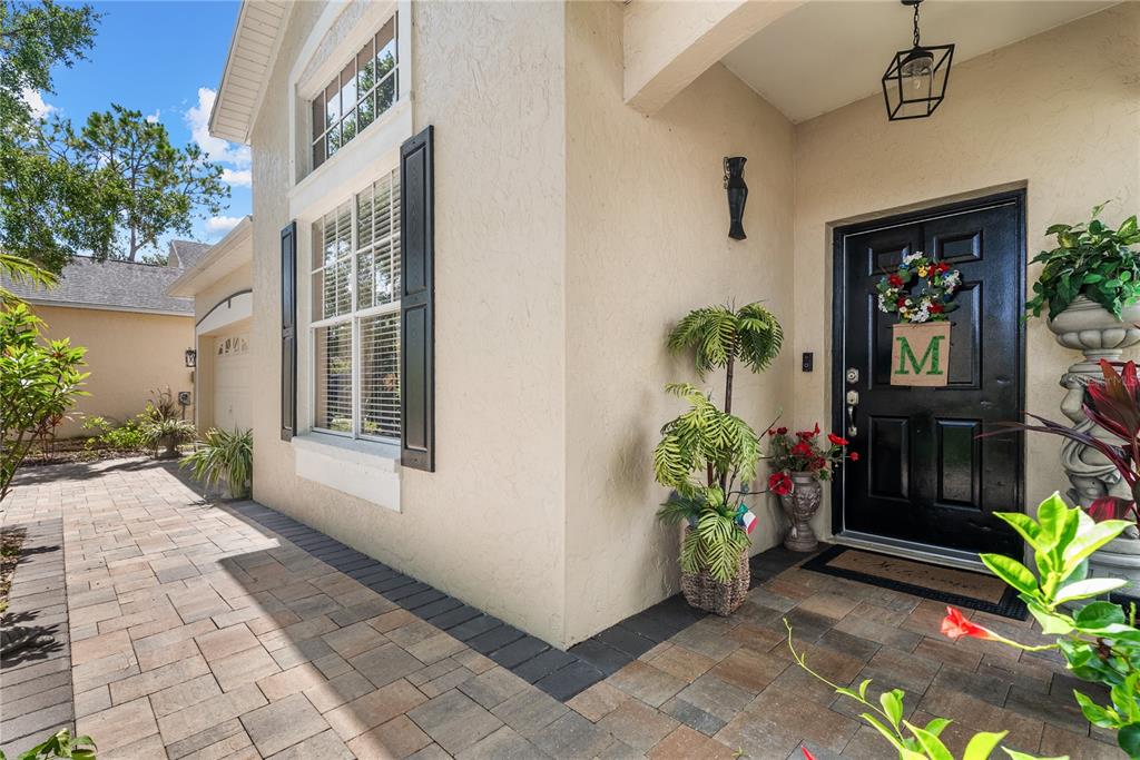 A paved walkway leads to the front entrance of a house with a black door — 11326 BLUE SAGE PLACE, LAKEWOOD RANCH, FL