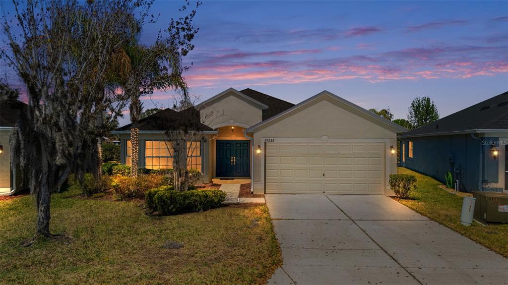 A single-story suburban house with a beige stucco exterior, a two-car garage, and landscaping — 29232 COHARIE LOOP, SAN ANTONIO, FL