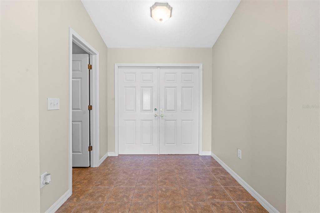 An entryway features light-colored walls, a tiled floor, and a set of white double doors — 29232 COHARIE LOOP, SAN ANTONIO, FL