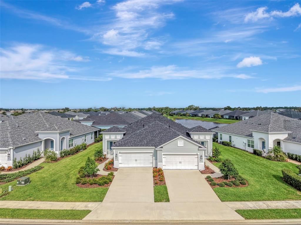 An exterior view of a single-story duplex home with two garages and a grassy lawn — 4842 WILLOW BEND AVENUE, PARRISH, FL