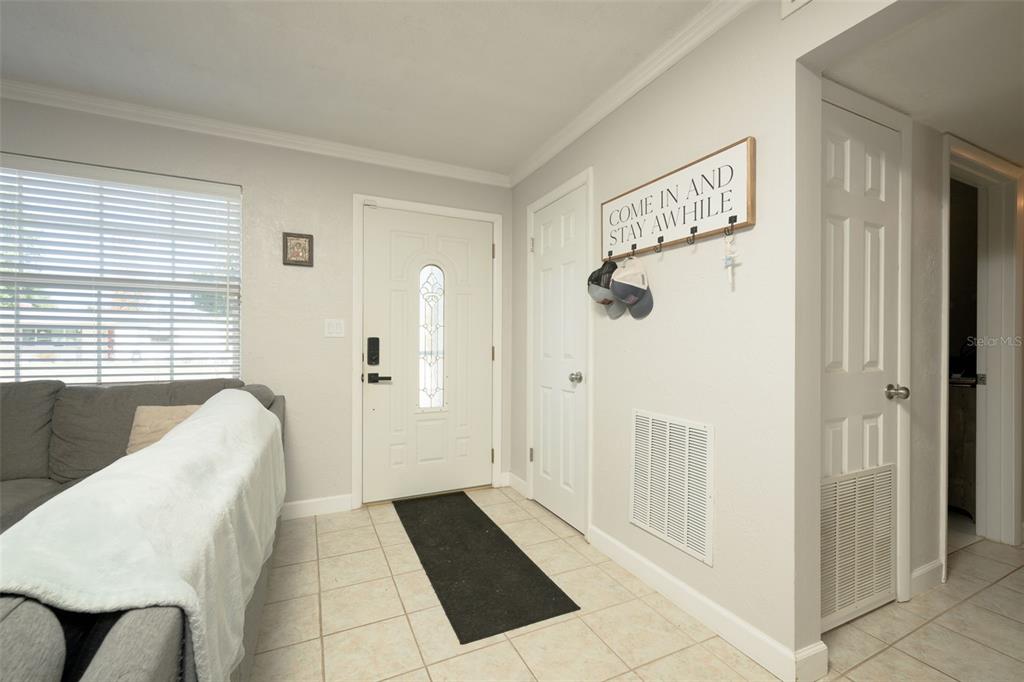 An entryway features a white front door, tile flooring, a coat rack, and a sofa — 76 S CAPRI DRIVE, ORMOND BEACH, FL