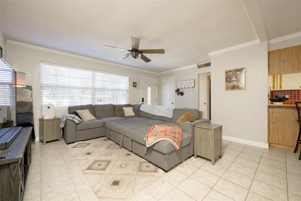 A living room features a large gray sectional sofa, a patterned rug, and tile flooring — 76 S CAPRI DRIVE, ORMOND BEACH, FL