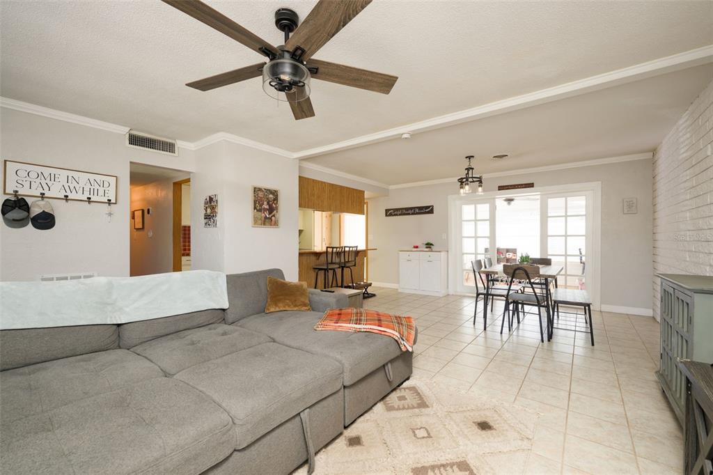 A living room with a gray sectional sofa, tile flooring, and a dining area beyond — 76 S CAPRI DRIVE, ORMOND BEACH, FL