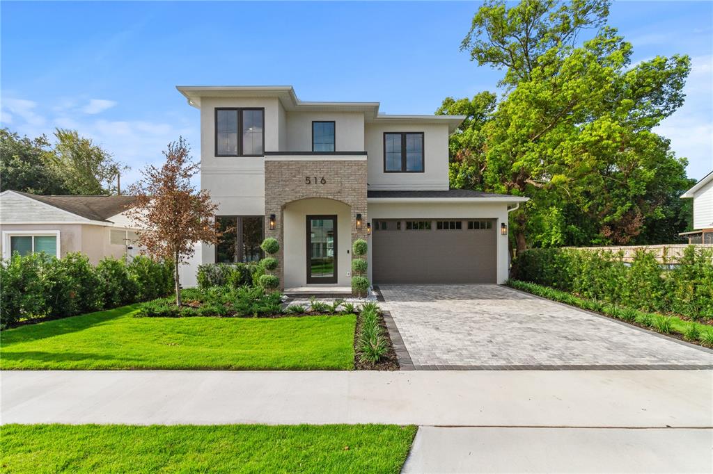 A two-story modern house features a stone-accented entryway, a paved driveway, and a manicured lawn — 516 CLAYTON STREET, ORLANDO, FL