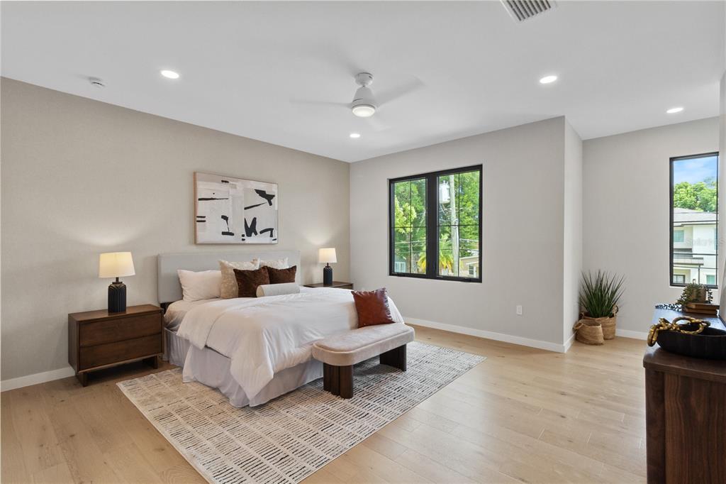 A modern bedroom features a king bed, light wood floors, and large black-framed windows — 516 CLAYTON STREET, ORLANDO, FL