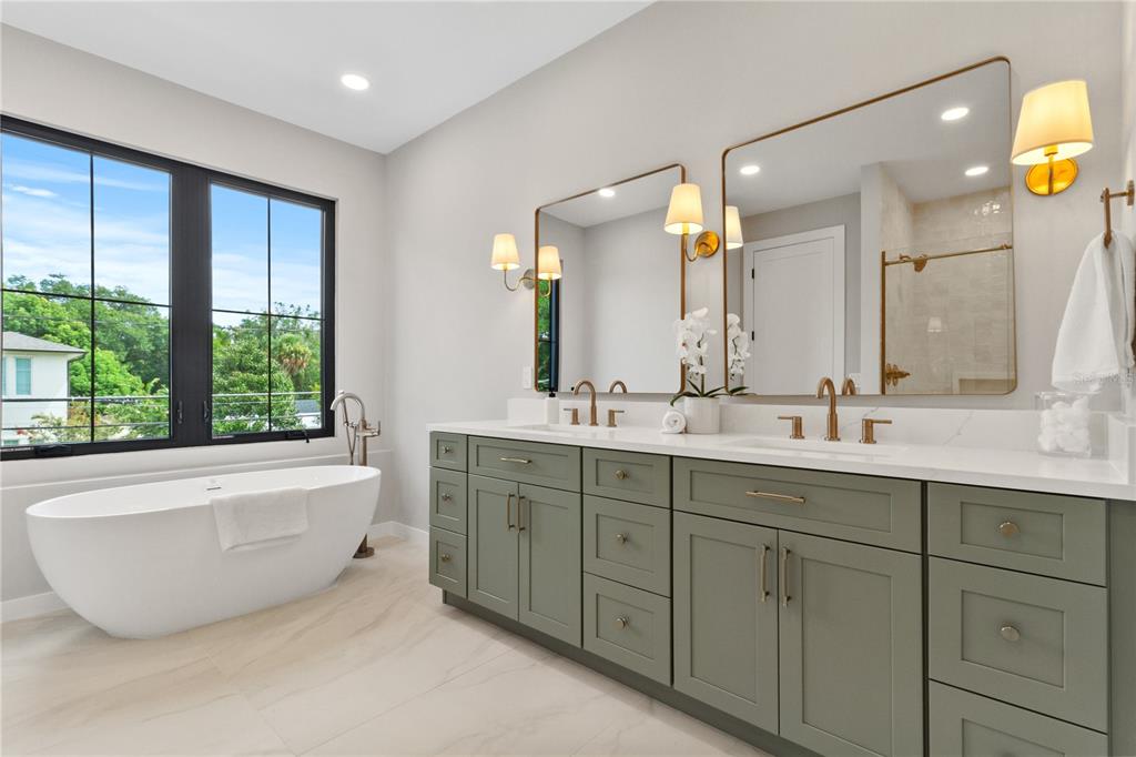 A modern bathroom features a sage green double vanity, a freestanding tub, and gold fixtures — 516 CLAYTON STREET, ORLANDO, FL